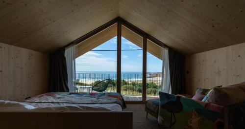 una camera da letto con una grande finestra con vista sull'oceano di Doniños Nature a La Coruña