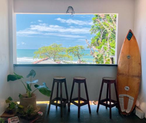 a window with a surfboard and stools in a room at LahSelva Pousada Hostel in Itacaré