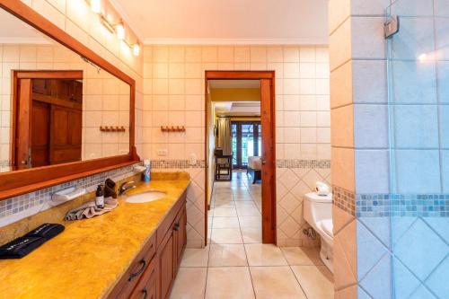 La salle de bains est pourvue d'un lavabo, d'un miroir et de toilettes. dans l'établissement Jade Coast #3- Private 5 Bedroom Villa, à Tamarindo