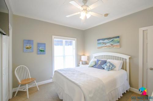 泰碧島的住宿－Beachfront Oasis At Tybee Island，一间卧室配有一张带吊扇和窗户的床。