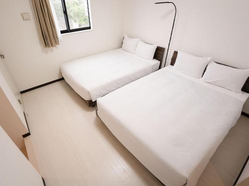 a small room with two beds and a window at KARCHIBE ISHIGAKI in Ishigaki Island