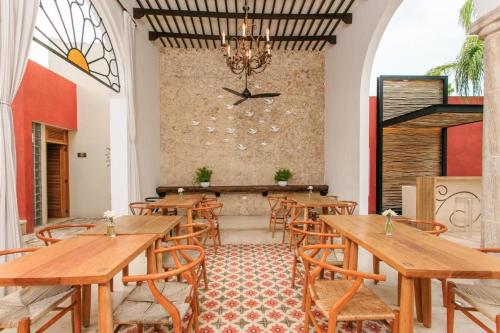 a restaurant with wooden tables and chairs and a chandelier at Más Palomas Concept House by Paloma's Hotels - Adults Only in Mérida