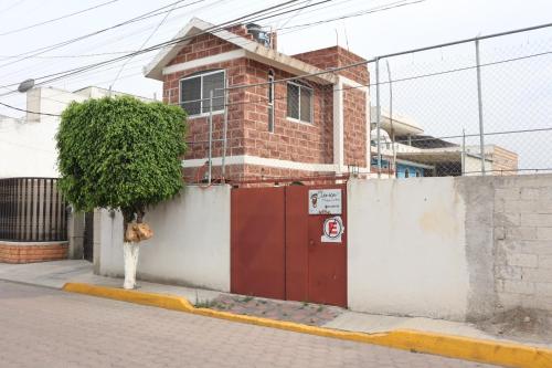 een stenen huis met een rode deur aan de kant van een straat bij KOLSA in Santa María Tonantzintla