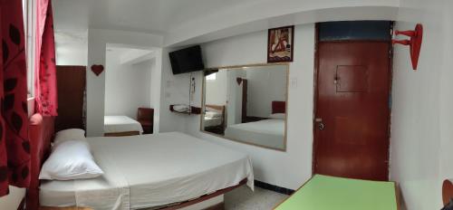 Habitación pequeña con 2 camas y espejo. en Hostal Reyna, en Lima