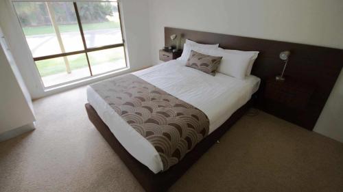 a bedroom with a large bed with a large window at Sunraysia Resort Mildura in Mildura