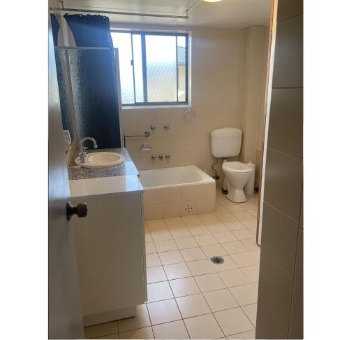 a bathroom with a tub and a toilet and a sink at Bowling Green 7 in Tuncurry