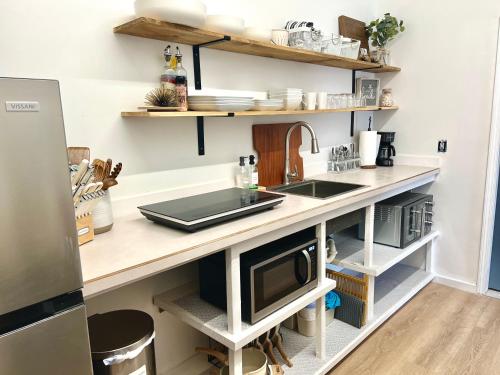 a kitchen with a counter with a sink and shelves at Hale ‘Aina (Country Cottage) in Keaau