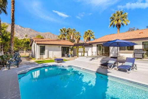 a swimming pool in front of a house with palm trees at Chateau Monroe - Walk to dwtn Palm Springs in Palm Springs