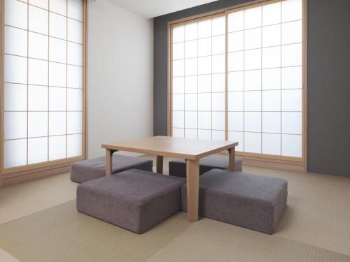 einen Tisch und Bänke in einem Zimmer mit Fenstern in der Unterkunft MIMARU TOKYO UENO INARICHO in Tokio