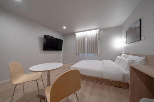 a hotel room with a bed and a table and chairs at Cheonan Aank Hotel Seongjeong in Cheonan
