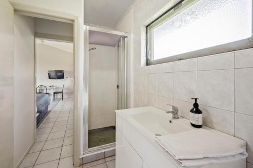 a white bathroom with a sink and a window at Jack & Di's Lakefront Motel in Rotorua