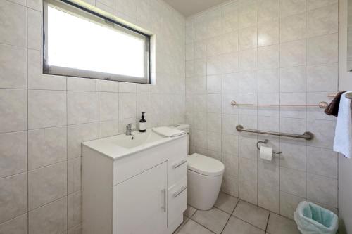a white bathroom with a toilet and a window at Jack & Di's Lakefront Motel in Rotorua
