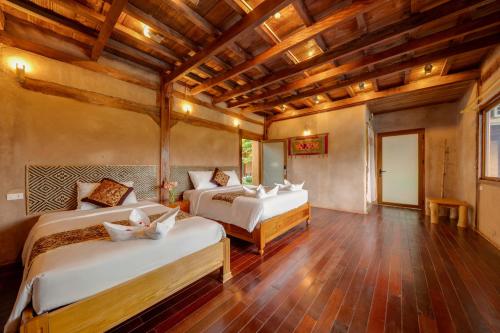 a bedroom with two beds and a wooden ceiling at Mai Chau Onsen Retreat in Mai Chau