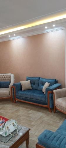 a living room with a blue couch and two chairs at Hotel appointment service in ‘Izbat Jamaşah al Gharbīyah