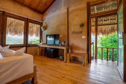 a bedroom with a bed and a desk with a television at Mai Chau Onsen Retreat in Mai Chau