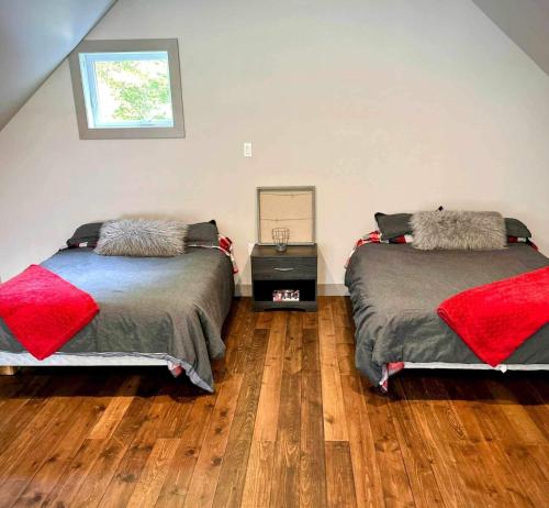 a bedroom with two beds and a wooden floor at Chalet Le Shack in Stratford
