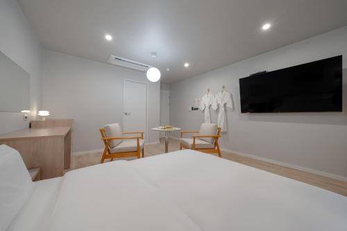 a bedroom with a white bed and a flat screen tv at Cheonan Aank Hotel Seongjeong in Cheonan