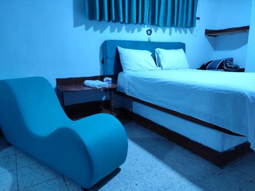 Habitación azul con cama y silla en Hostal Reyna, en Lima