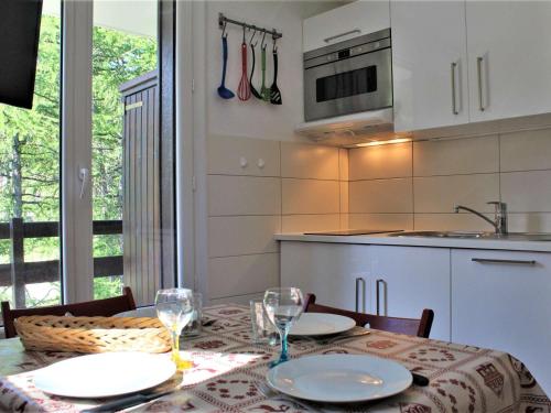 une cuisine avec une table avec des assiettes et des verres à vin dans l'établissement Studio 4 pers. avec balcon sud, calme, parking gratuit - Risoul 1850 - FR-1-330-567, à Risoul