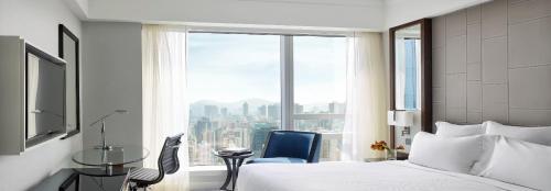 a bedroom with a bed and a chair and a window at Cordis, Hong Kong in Hong Kong