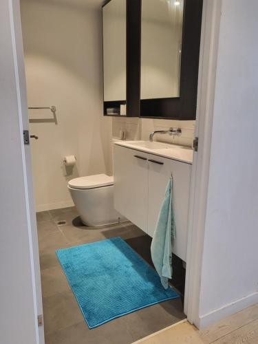 a bathroom with a sink and a toilet and a blue rug at 1 BEDROOM STUNNING VIEW APARTMENT in Melbourne