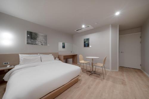 a bedroom with a white bed and a table and chairs at Cheonan Aank Hotel Seongjeong in Cheonan