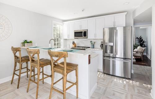 a kitchen with white cabinets and a stainless steel refrigerator at Charming Secluded Courtyard - 1 BLOCK TO KING in Charleston
