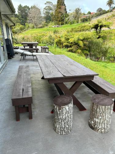 a wooden picnic table and two benches and trees at Almost Heaven BNB in New Plymouth