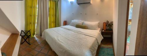 a bedroom with a bed with yellow curtains at Morrocoy - Acogedora Casa VIP Tucacas in Tucacas