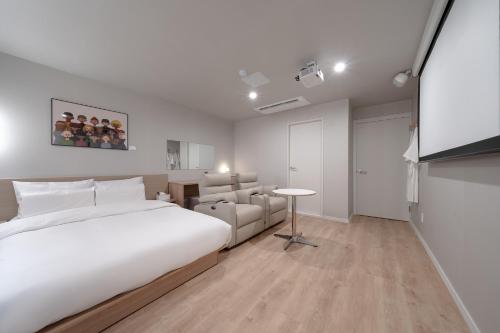 a bedroom with a large white bed and a table at Cheonan Aank Hotel Seongjeong in Cheonan