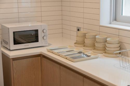 a microwave sitting on a counter next to a pile of plates at Cheonan Aank Hotel Seongjeong in Cheonan