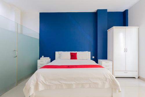 a bedroom with a blue wall and a white bed at RedDoorz Plus near Living Plaza Jababeka in Bekasi