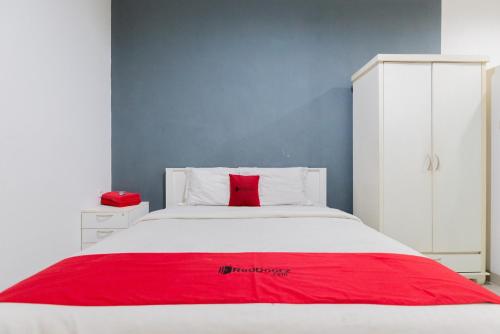 a bedroom with a white bed with a red blanket at RedDoorz Plus near Living Plaza Jababeka in Bekasi