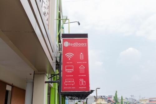 a red sign hanging from the side of a building at RedDoorz Plus near Living Plaza Jababeka in Bekasi