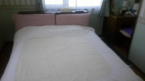a bed with a white blanket on top of it at ホテルていね in Sapporo