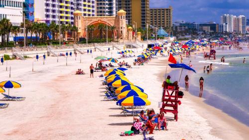 a beach with chairs and umbrellas and people on it at Pirates Cove 4th Floor Balcony Remodeled Condo in Daytona Beach