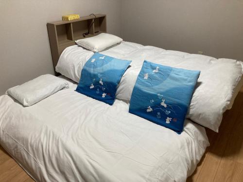 uma cama branca com duas almofadas azuis em Sky Tree INN (晴樹宿）stay ASAKUSA em Tóquio