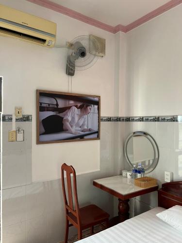 a room with a tv on a wall with a table at Mai Phương Thúy Motel in Bien Hoa