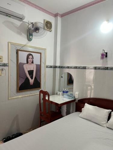 a bedroom with a bed and a table and a picture of a woman at Mai Phương Thúy Motel in Bien Hoa