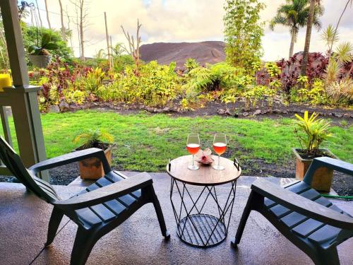 two chairs and a table with two glasses of wine at Unique Lava House by steaming crater in Pahoa
