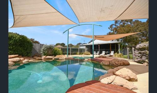 a swimming pool with an umbrella in a yard at Pomonal Cottages Grampians in Halls Gap