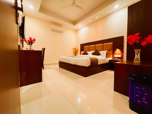 Hotel Olive Vault, Most Awarded Property in Haridwar في حاريدوار: غرفة نوم بسرير وزهور في غرفة