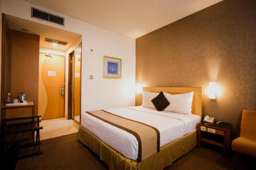 a hotel room with a bed and a chair at Serela Riau by KAGUM Hotels in Bandung