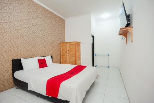 1 dormitorio con 1 cama con manta roja y blanca en RedDoorz Syariah near Jatisampurna Hospital, en Bekasi