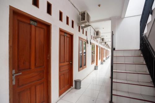 an empty corridor with wooden doors in a building at RedDoorz Syariah near Jatisampurna Hospital in Bekasi