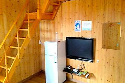 UllŭngにあるHaeoreum Pensionのテレビ、冷蔵庫、階段が備わる客室です。