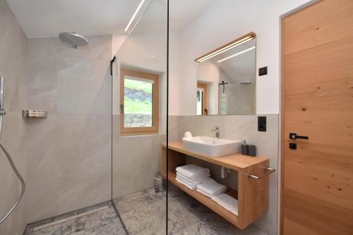 シランドロにあるSonnwarthofのバスルーム(洗面台、ガラス張りのシャワー付)