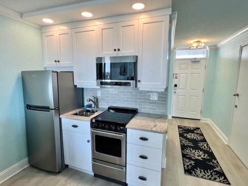 a kitchen with white cabinets and a stainless steel refrigerator at Pirates Cove 4th Floor Balcony Remodeled Condo in Daytona Beach