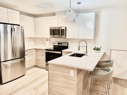 uma cozinha com armários brancos e um frigorífico de aço inoxidável em Modern 2 Bed Furnished Apartment in Quincy em Quincy