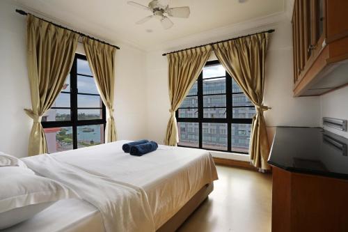 a bedroom with a bed and two large windows at KK Vacation Apartments@Marina Court Resort Condominium in Kota Kinabalu